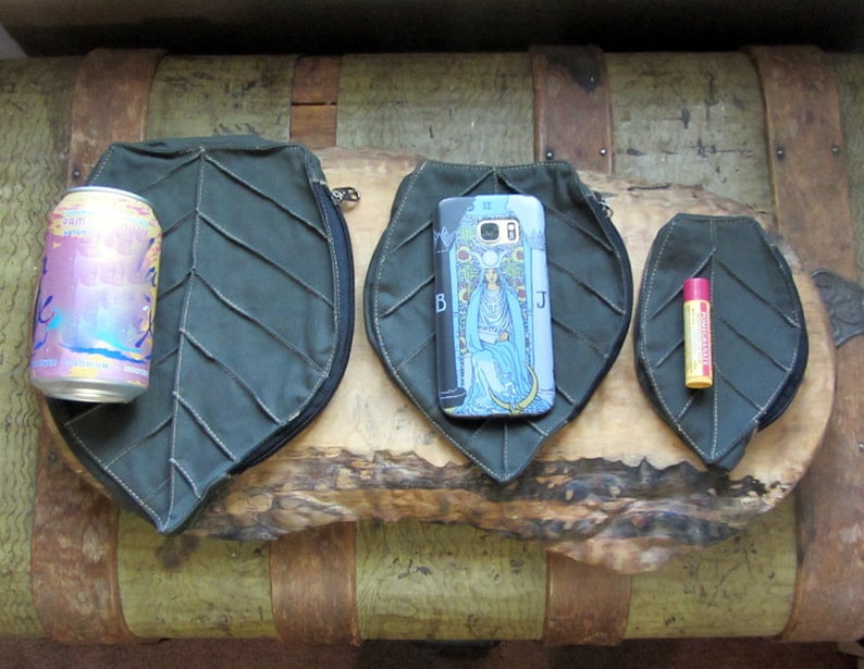 May include: Three green leaf-shaped zippered pouches of different sizes. The largest pouch is large enough to hold a can of sparkling water. The middle pouch is large enough to hold a smartphone. The smallest pouch is large enough to hold a lip balm.