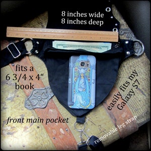 May include: Black canvas hip bag with a large front pocket, a removable leg strap, and a zippered pocket. The bag measures 8 inches wide and 8 inches deep. The text "fits a 6 3/4 x 4" book" and "easily fits my Galaxy S7" is printed on the bag.