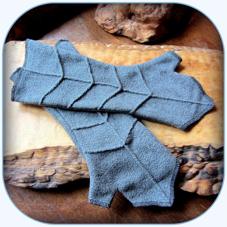 May include: A pair of grey fingerless gloves with a geometric pattern. The gloves are made of a soft, textured fabric.