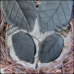 May include: Four leaf-shaped fabric pouches with zippers. Two pouches have contrast stitching, and two pouches have no contrast stitching. The pouches are arranged on a woven surface.