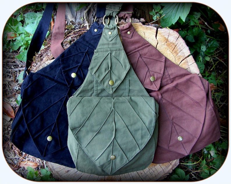 May include: Three canvas shoulder bags with leaf-shaped designs. The bags are in black, green, and brown.