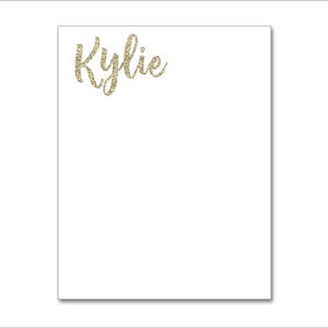 May include: A white notepad with the name "Kylie" written in gold glitter lettering.