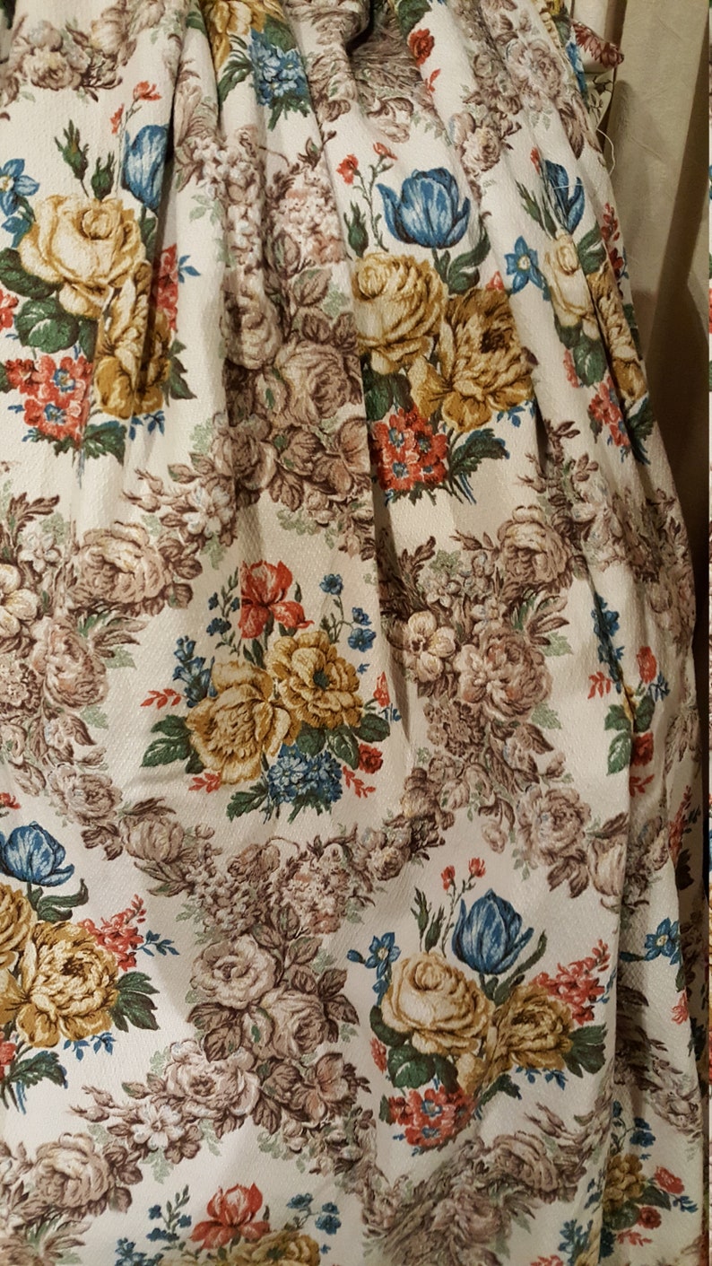 K&ouml;nnte beinhalten: Eine Nahaufnahme eines wei&szlig;en Stoffes mit einem Blumenmuster. Der Stoff zeigt eine Vielzahl von Blumen, darunter Rosen, Tulpen und kleinere Bl&uuml;ten. Die Blumen sind in den Farben Gelb, Rot, Blau und Braun gehalten.