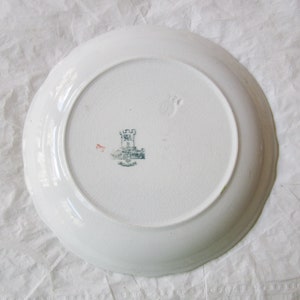 May include: White ceramic plate with a scalloped edge. The back of the plate has a green and black castle logo with the text "Royal Doulton" printed below.