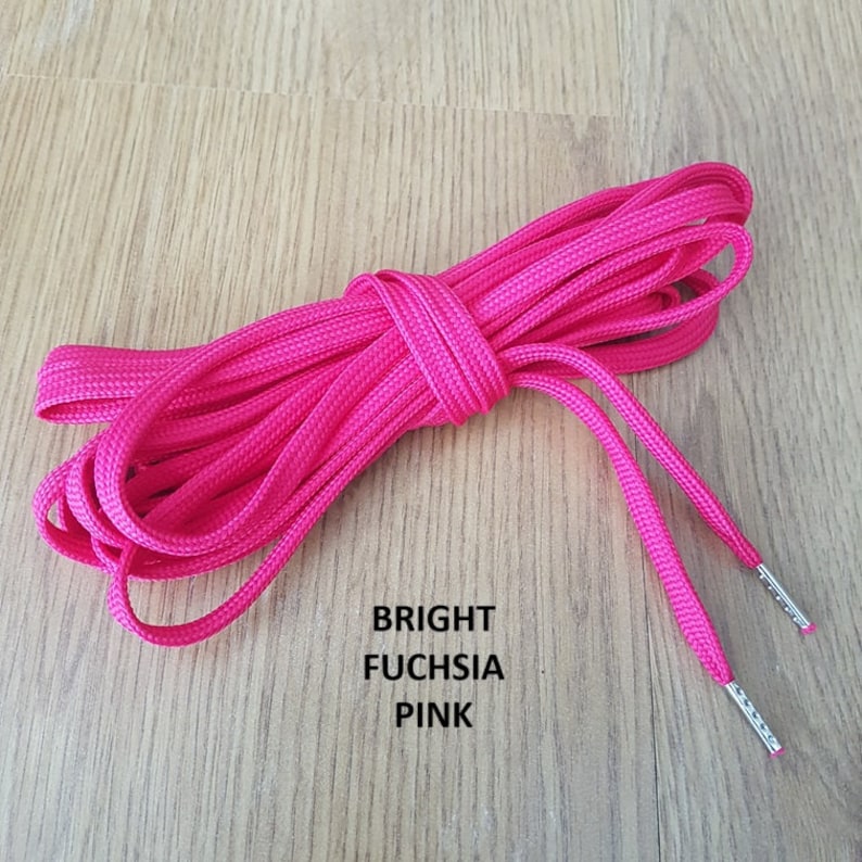 Puede incluir: Cordones de zapatos de color rosa fucsia brillante con aglets plateados. Los cordones est&aacute;n enrollados y atados juntos.