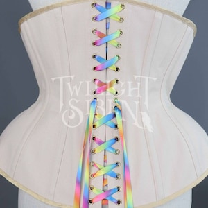 May include: A beige corset with a rainbow ribbon lacing up the back. The corset has a wide, flared skirt and is made of a smooth, sturdy fabric.