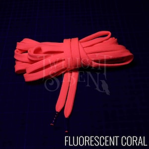 Puede incluir: Primer plano de un cord&oacute;n de zapato de color coral fluorescente, atado en un nudo. El cord&oacute;n est&aacute; hecho de un material suave y plano, perfecto para a&ntilde;adir un toque de color a cualquier zapato.