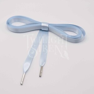 May include: Light blue satin ribbon shoelaces with silver aglets. The ribbon is folded in half and tied in a bow.