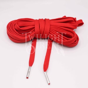 May include: Red shoelaces with silver aglets. The laces are made of a thick, woven material.
