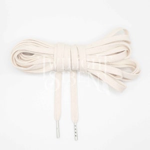 May include: A pair of off-white cotton shoelaces with silver metal aglets.