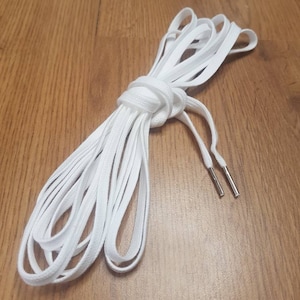 May include: White shoelaces with silver aglets. The laces are flat and woven.