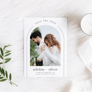 May include: A white save the date card with a black arch design and a photo of a couple embracing. The text reads "save the date" in a black script font. The couple's names are "Adeline & Oliver" and the date is "9.24.21" with the location "Lafayette, LA". The text "formal invitation to follow" is also included.