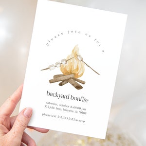Op de afbeelding: Een witte uitnodigingskaart met een aquarelillustratie van een kampvuur met marshmallows op stokken. De tekst luidt "Kom gezellig met ons mee voor een kampvuur in de tuin" en bevat de datum, tijd, adres en RSVP-informatie.