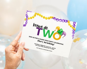 May include: A white invitation card with purple and gold beads at the top. The text on the card reads "Krewe de TWO" with a green and purple jester hat. The invitation is for a Mardi Gras party celebrating Oliver's 2nd birthday. The party is on Saturday, February 18th from 2:00 to 4:00 PM at 555 Julie Lane, Lafayette, LA 70508. The text also says to text Reagan at 337-888-8888 to RSVP.