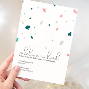 May include: A white invitation card with a terrazzo pattern in shades of pink, teal, and gray. The text on the card reads "adeline richard is turning 21. Join us as we celebrate. saturday, april 6 8:00 pm 5 julie lane ayette, la 70508"