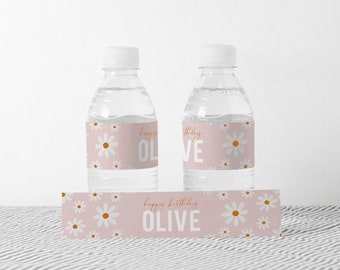 May include: Two clear plastic water bottles with pink and white daisy patterned labels that say "Happy Birthday Olive". There is also a matching label with the same pattern that says "Happy Birthday Olive".