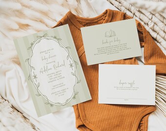 May include: A baby shower invitation with a floral wreath design and text, alongside two cards and a rust-colored onesie. The invitation includes details for the event, such as the date, time, and location.