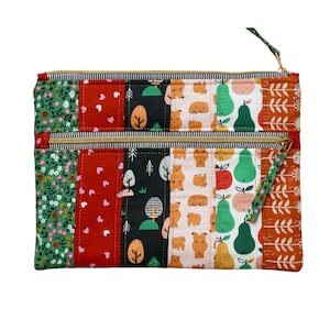 Puede incluir: Una bolsa de doble cremallera con un dise&ntilde;o de patchwork. La tela presenta una variedad de patrones, incluyendo estampados florales, geom&eacute;tricos y de animales. La bolsa est&aacute; hecha de tela acolchada y tiene una cremallera dorada.