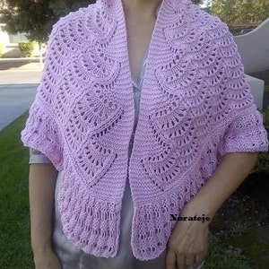 Może przedstawiać: Różowy, ażurowy szal wykonany na drutach. Szal jest zarzucony na ramiona osoby i noszony jako modny dodatek.