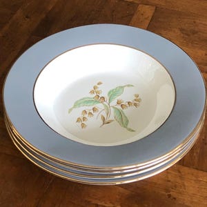 May include: A set of three blue and white soup bowls with a gold rim and a floral design. The bowls are stacked on top of each other.