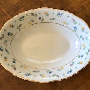 May include: White oval serving bowl with a gold rim and a floral pattern in shades of yellow, blue, and pink.