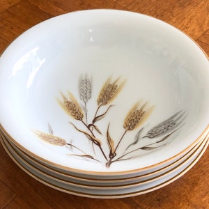 May include: A set of three white ceramic bowls with a gold rim and a wheat design. The bowls are stacked on top of each other.