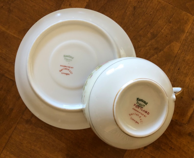 Puede incluir: Una taza de t&eacute; y un platillo blancos con un borde dorado. La parte inferior de la taza y el platillo tienen la marca comercial Haviland France y las palabras "Decorado por Haviland & C Limoges".