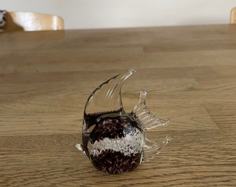 May include: A glass figurine of a fish with black and white speckled glass. The fish is clear glass with a black and white speckled body.