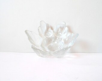 May include: A clear glass bowl shaped like a flower with five petals. The bowl is designed to hold small items, such as jewelry or trinkets.