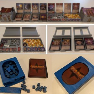 May include: A gray 3D-printed board game organizer set featuring modular trays for cards and tokens, alongside a blue 3D-printed deck box with a cutout window and small blue cubes for game components, shown in various configurations.