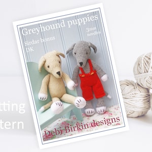 Può includere: Schema di lavoro a maglia per due cuccioli di levriero. Lo schema è intitolato "Greyhound puppies" e include il testo "Sirdar bonus DK" e "3mm needles". Lo schema è di "Debi Birkin designs".