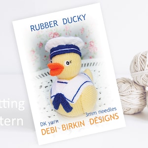 May include: Knitting pattern for a yellow rubber ducky wearing a blue and white sailor hat. The pattern is called "Rubber Ducky" and is by "Debi Birkin Designs".