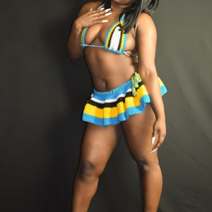 Peut inclure: Une femme portant un haut de bikini et une jupe en crochet bleu, jaune, noir et blanc. La jupe est une mini-jupe avec un ourlet à volants. Elle porte des talons hauts blancs.