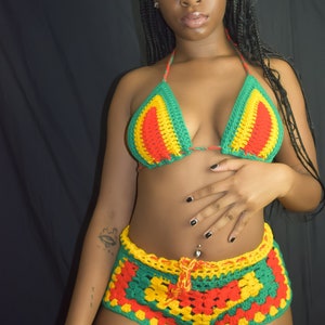 Może przedstawiać: Komplet bikini wykonany na szydełku w kolorze czerwonym, żółtym i zielonym. Górna część to trójkąt, a dolna część to wysokie szorty.