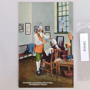 May include: Vintage postcard depicting a barber and peruke maker's shop in Williamsburg, Virginia. The scene shows a barber attending to a customer wearing a white wig. The shop is furnished with a bench, chairs, and a table with tools. The text at the bottom reads: "The Barber and Peruke Maker's Shop, Williamsburg, Virginia."