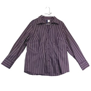 May include: A long-sleeved button-down shirt featuring a vertical striped pattern in shades of dark purple, black, and white. The shirt has a classic collar, a front button placket, and wide cuffs on the sleeves, displayed on a white hanger.