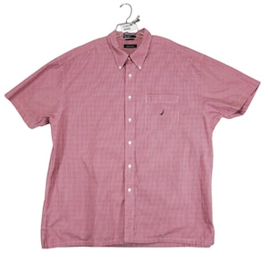 May include: A short-sleeved button-down shirt in a red and white micro-check pattern. The shirt features a button-down collar, a front button placket, and a single chest pocket with a small dark blue embroidered sailboat logo on the pocket.