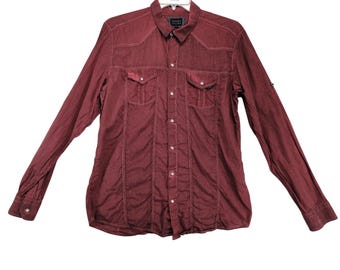 May include: A burgundy long-sleeve shirt with a button-down front, two chest pockets, and white stitching details. The shirt is hanging on a hanger against a white background. The shirt has a classic western style.