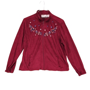 May include: A red zip-up jacket with embroidered floral details. The jacket has a stand-up collar and a zipper closure. The embroidery is in shades of blue, white, and green.