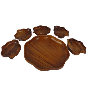 May include: A set of six wooden serving bowls, featuring a large, round bowl with five smaller, leaf-shaped bowls. The bowls are made of dark brown wood with a natural grain pattern.