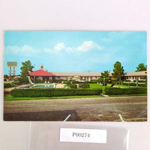 May include: Vintage postcard featuring a motel with a red roof, swimming pool, and playground. The sky is blue with a few clouds. The motel sign reads "Johnson's". The postcard has a retro aesthetic.