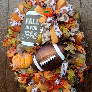 May include: A brown and orange fall wreath with a football theme. The wreath is decorated with fall leaves, pumpkins, and a football. The sign on the wreath says "Fall is for Football".