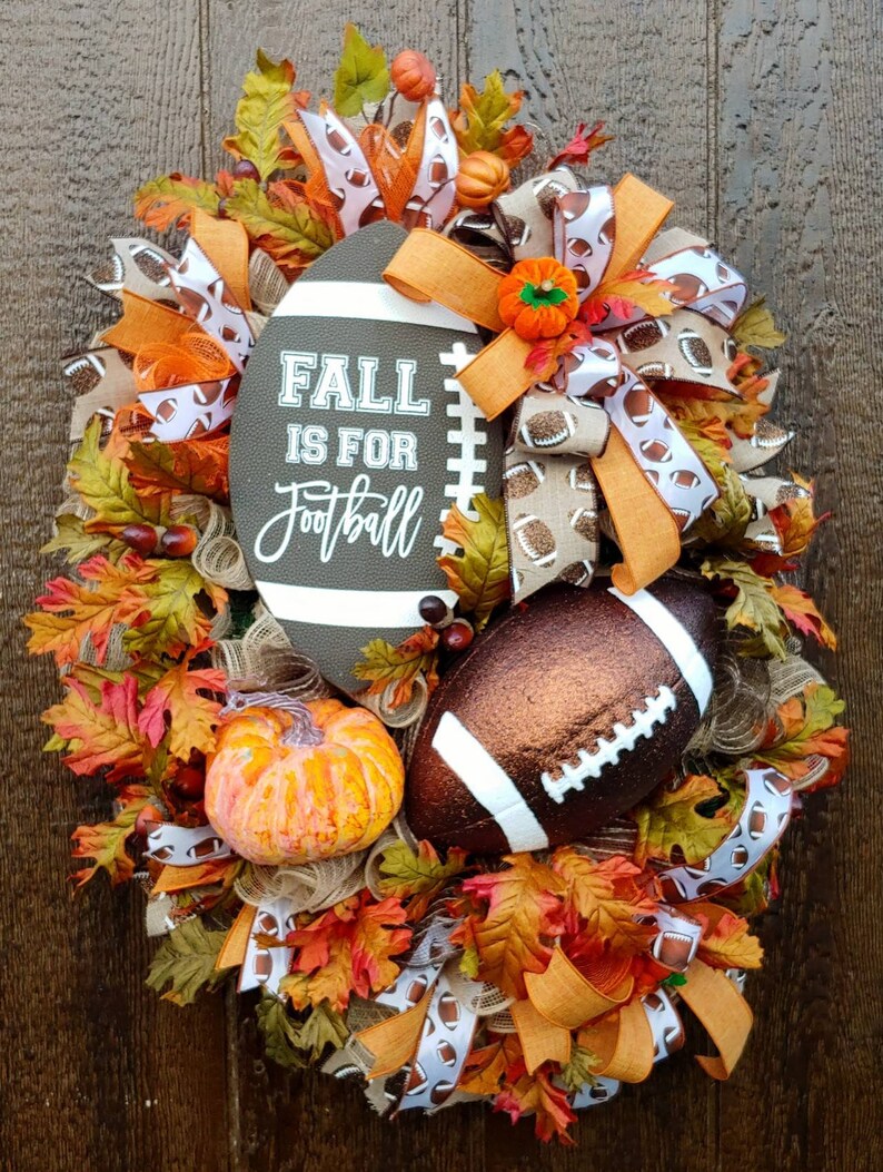 May include: A fall-themed wreath with a brown football, orange and white ribbon, and the text "Fall is for Football".
