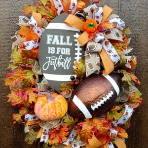 May include: A fall-themed wreath with a brown football, orange and white ribbon, and the text "Fall is for Football".