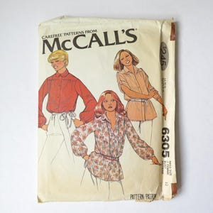Peut inclure: Une pochette de patron de couture vintage McCall's, numéro 6305, présentant des illustrations de trois styles de chemisiers différents. La couverture affiche la marque, le numéro du patron et un prix de 2,45 $, avec des dessins de chemises unies rouges et à motifs floraux.