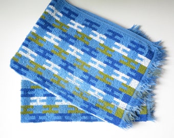 May include: Two blue and white bath towels with a geometric pattern in green, blue, and white. The towels have a fringed edge.