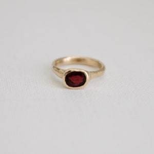 May include: A gold ring with a red gemstone set in the center.