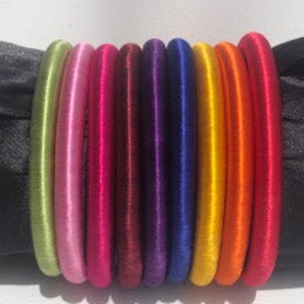 Silk tread bangles are  embellished with gold ribbon come in a rainbow of colors. They are 2.5" wide with a silky soft fit.