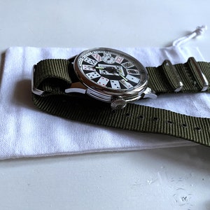 May include: A silver watch with a white face and a green nylon strap. The watch face features a design of playing cards.
