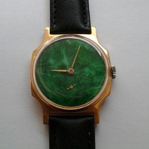 May include: A gold-tone wristwatch with a green marble-patterned face and black leather band.